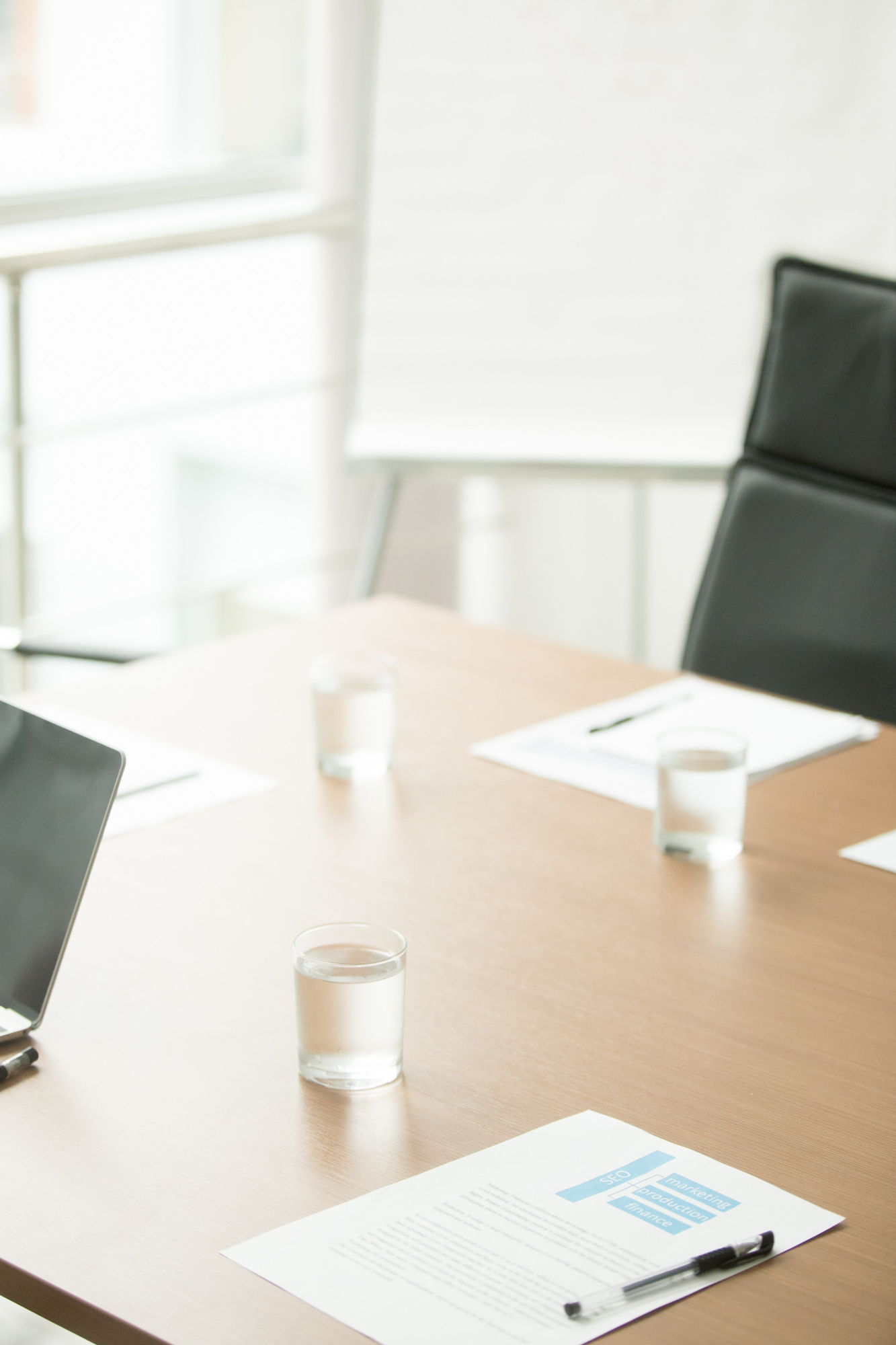 Conference room desk with chairs, documents, pens, and water glasses